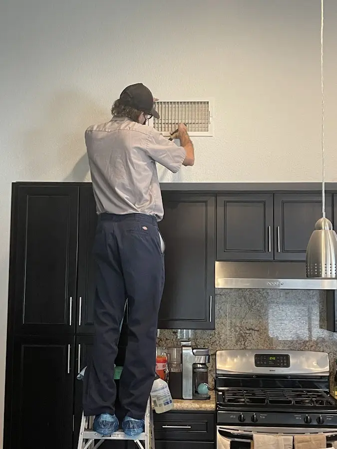 Technician inspecting an air vent during HVAC service in North Hempstead